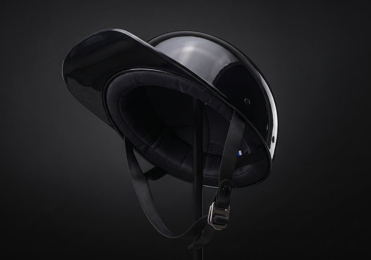 Velmurax baseball cap style helmet in gloss black, tipped back to show the lining and chin strap