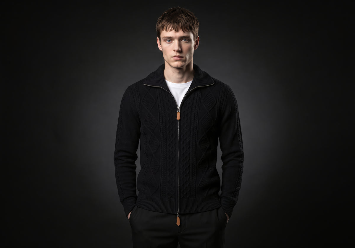 Velmurax cable knit zip cardigan in black, worn by the model in a front view on the dark studio set