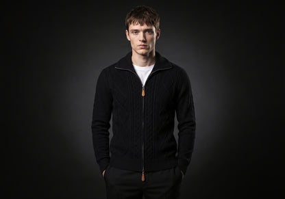 Velmurax cable knit zip cardigan in black, worn by the model in a front view on the dark studio set