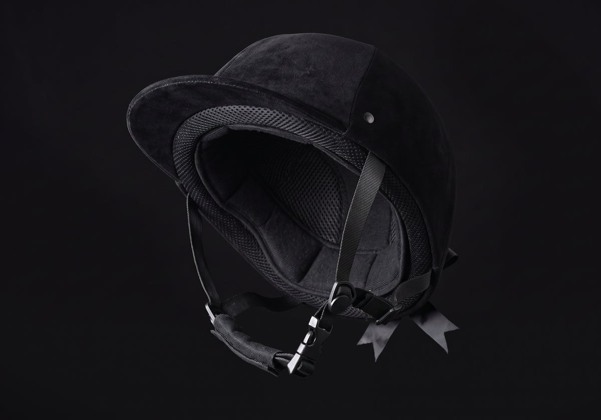 Velmurax classic velvet riding helmet in black velvet, tipped back to show the lining and chin strap