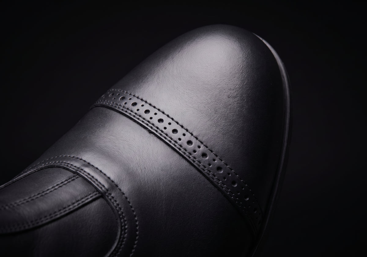 Velmurax cowhide paddock boots in black, the stitched toe cap up close, worn
