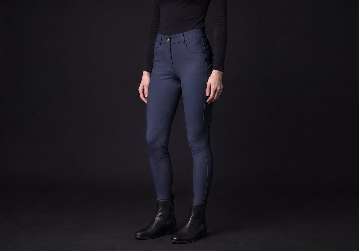 Velmurax full-seat riding breeches in navy, worn by a rider, seen from the ribcage down on the dark studio set