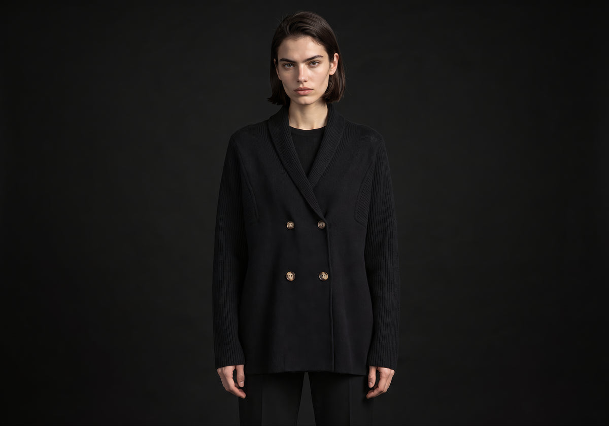Velmurax knit cashmere coat in black, worn by the model in a front view on the dark studio set