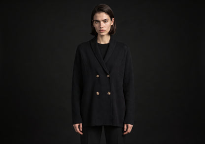 Velmurax knit cashmere coat in black, worn by the model in a front view on the dark studio set