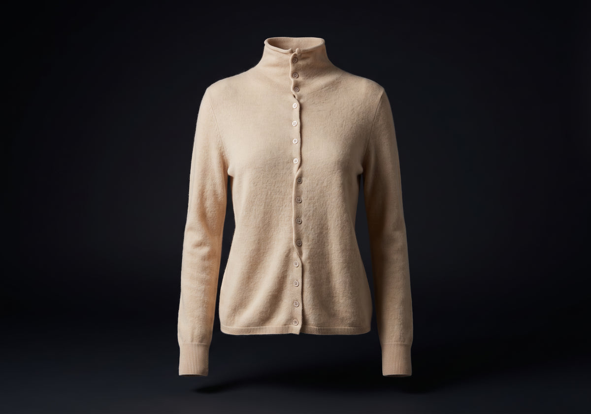 Velmurax mock neck cashmere cardigan in beige, on its own on the dark studio set