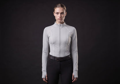 Velmurax women's long-sleeve riding top in light gray, worn by the model in a front view on the dark studio set