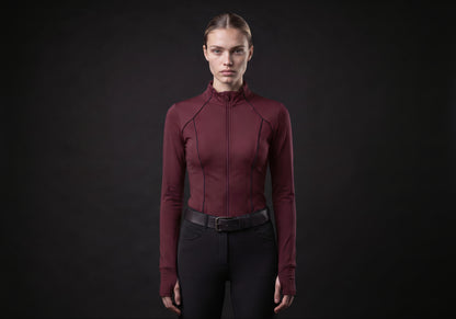 Velmurax women's long-sleeve riding top in burgundy, worn by the model in a front view on the dark studio set