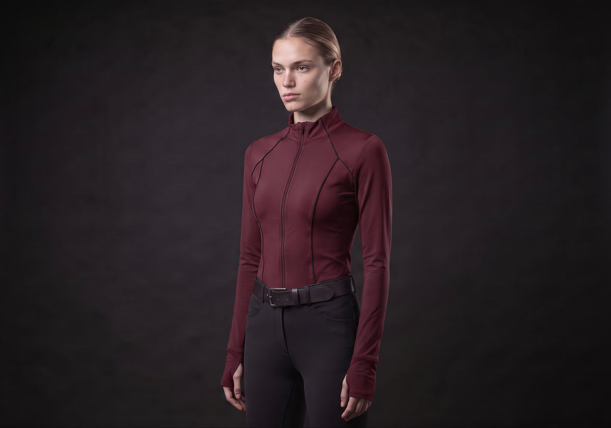 Velmurax women's long-sleeve riding top in burgundy, in a three-quarter view on the model on the studio set