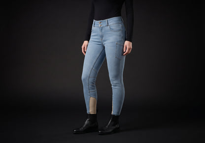 Velmurax women's high-waisted denim riding breeches in light blue, worn by a rider, seen from the ribcage down on the dark studio set