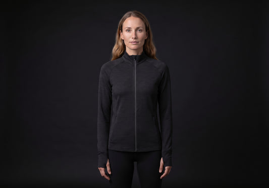 Velmurax women's stretch track jacket in black, worn by the model in a front view on the dark studio set