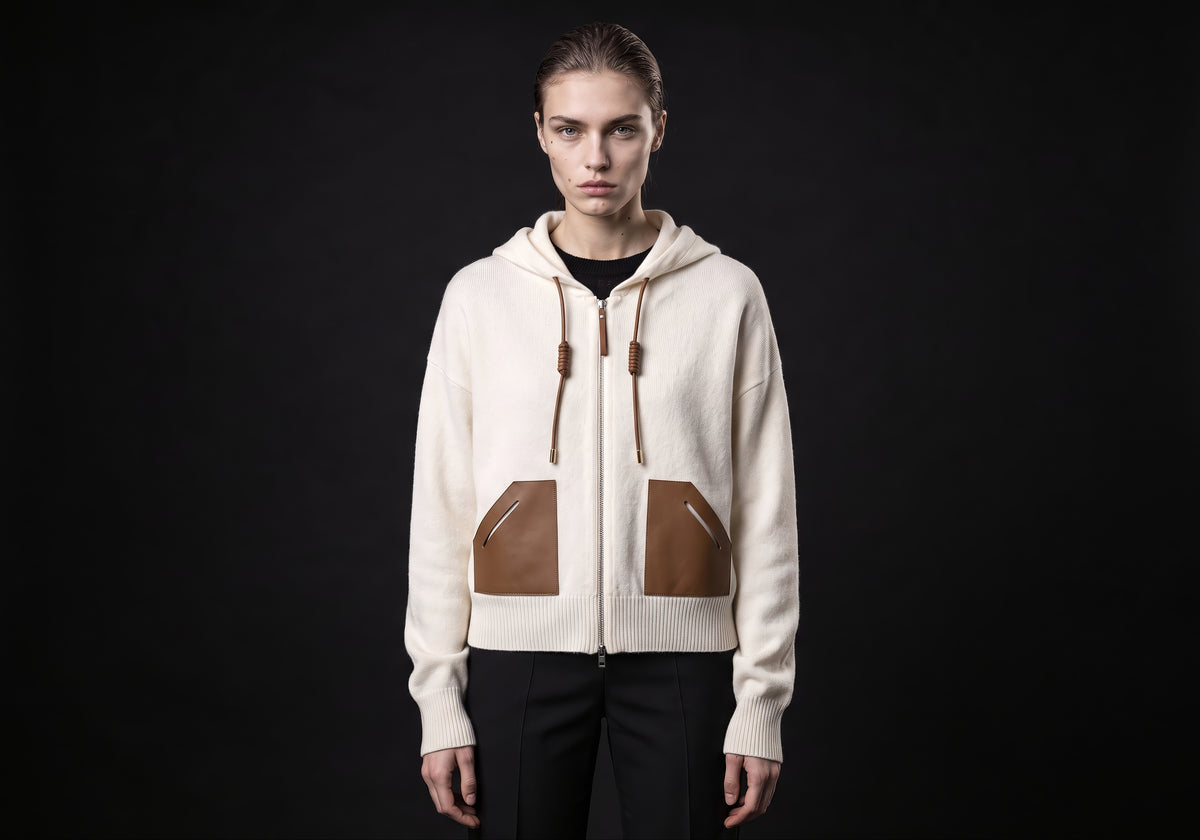 Velmurax wool cashmere zip hoodie in ivory, worn by the model in a front view on the dark studio set