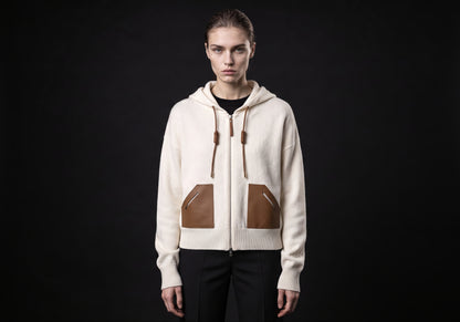Velmurax wool cashmere zip hoodie in ivory, worn by the model in a front view on the dark studio set