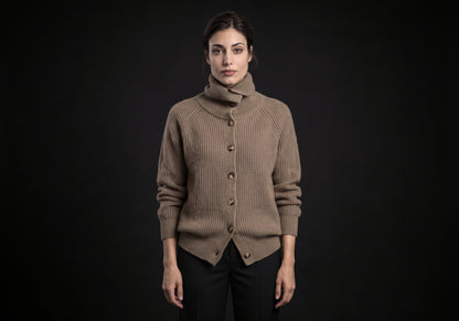 Velmurax wool turtleneck cardigan in taupe with the collar folded over, worn buttoned over black tailored trousers